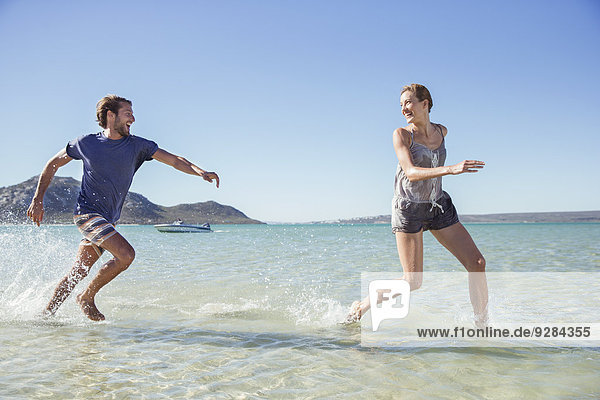 Couple running in waves on beach