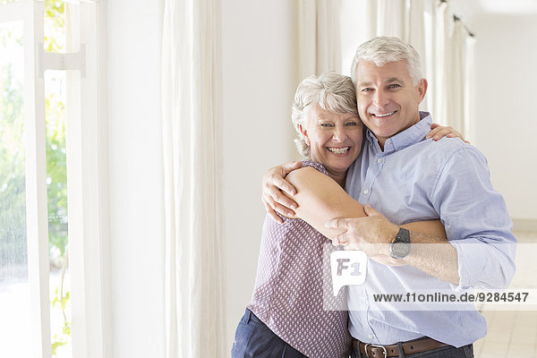 Ältere Paare umarmen sich im Wohnraum