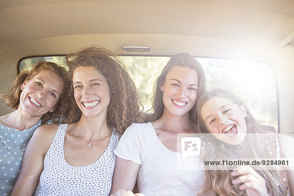 Vier Frauen sitzen auf dem Rücksitz des Autos.