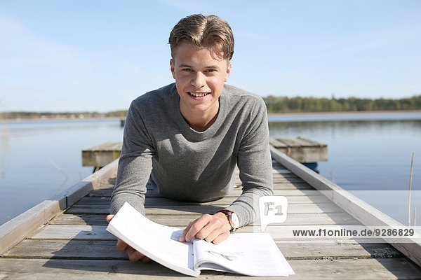 Young man reading on jetty