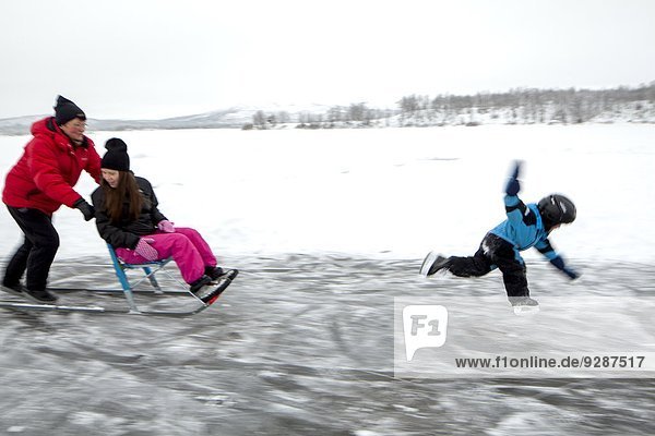Mother pushing sledge with girl