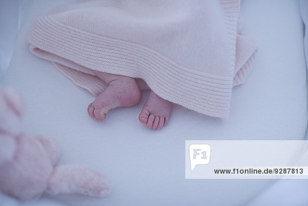 Neugeborene Babyfüße unter der Decke
