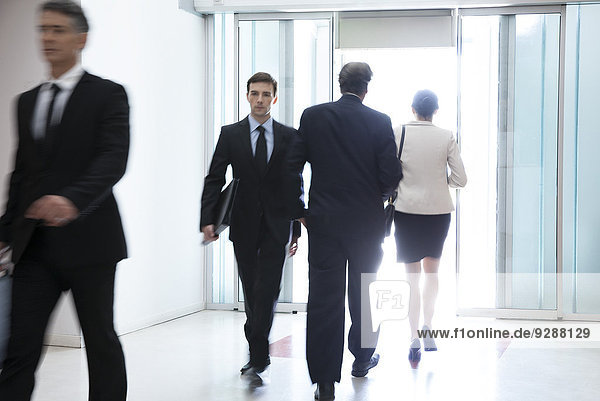 Business professionals passing through office building lobby