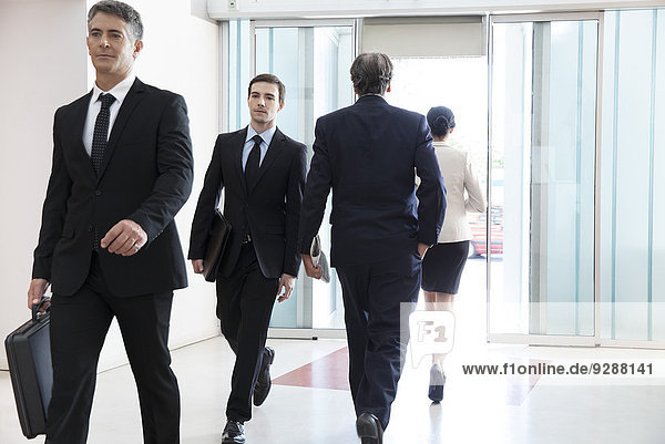 Business professionals passing through office lobby