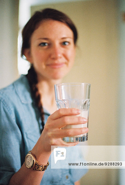 Eine Frau  die ein großes Glas Wasser hält.