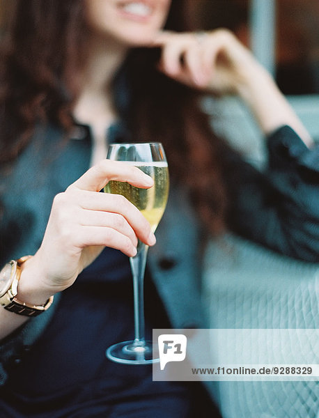 Eine Frau hält ein Glas Weißwein mit einem langen Stiel.