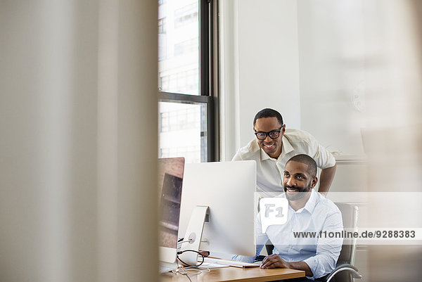 Zwei Männer schauen auf einen Computerbildschirm in einem Büro.