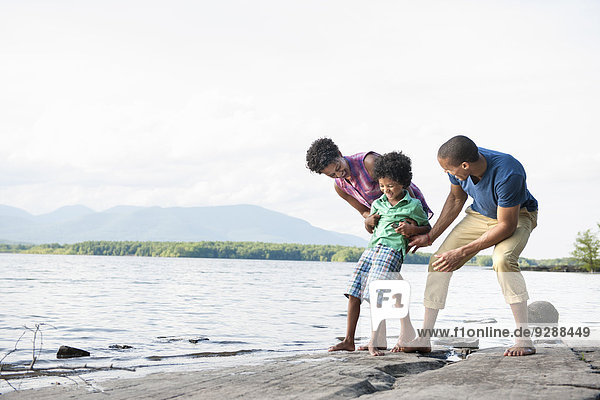 Eine Familie  Mutter  Vater und Sohn spielen am Ufer eines Sees.