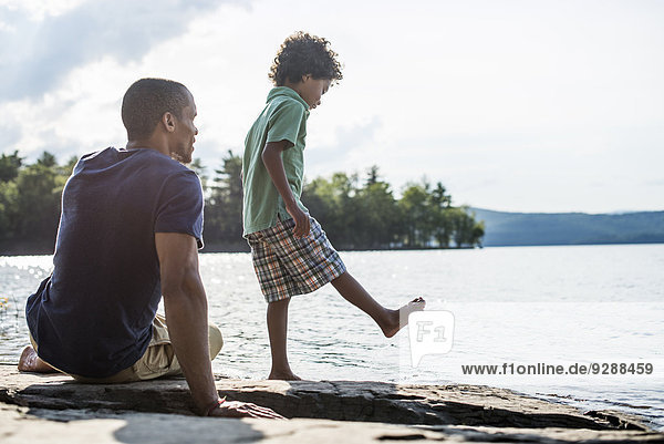 Ein Vater und Sohn an einem Seeufer im Sommer.
