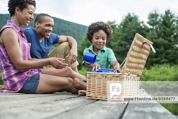 Eine Familie  die im Sommer ein Picknick an einem See macht.