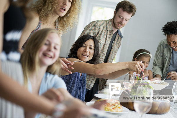 Ein Familientreffen zum Essen. Erwachsene und Kinder an einem Tisch.