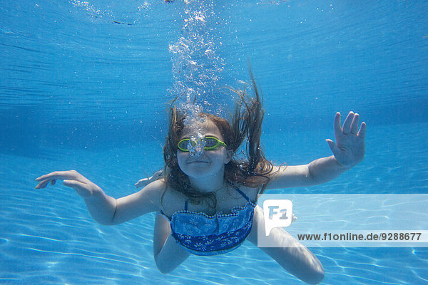 Ein Kind,  das in einem Schwimmbad unter Wasser schwimmt.