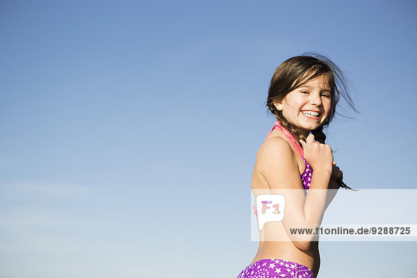 Ein kleines Kind im Bikini mit geflochtenen Haaren.