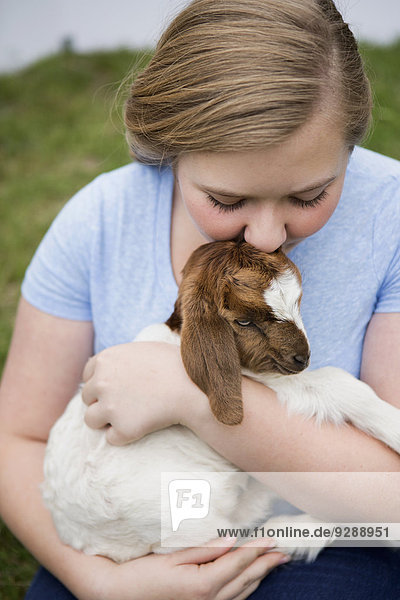 Ein Mädchen kuschelt ein Ziegenbaby.