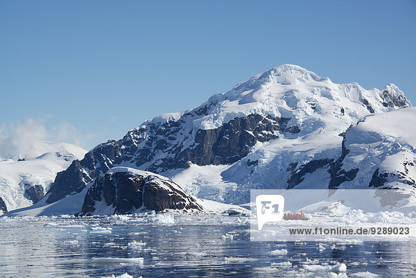 Ein kleines Boot  das auf dem Ozean zwischen Eisschollen vor der Küste einer Insel in der Antarktis treibt.