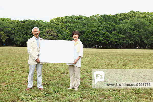 Senior adult Japanese couple with whiteboard in a park