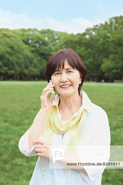 Senior adult Japanese woman with smartphone in a park