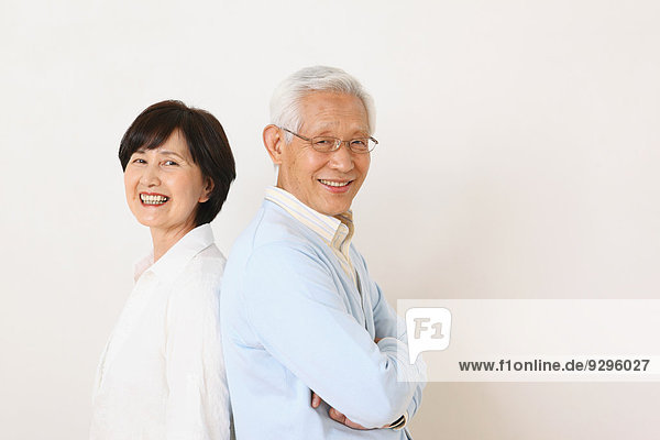 Senior adult Japanese couple against white wall