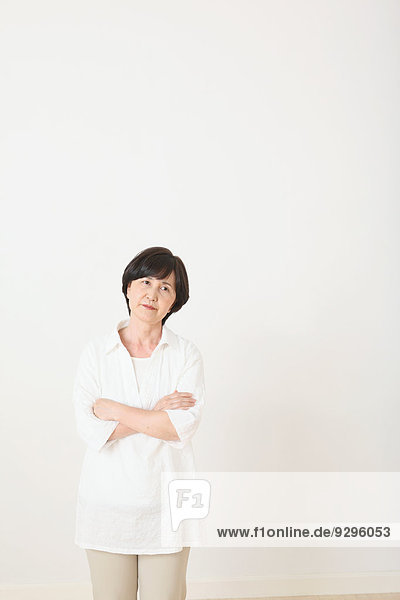 Senior adult Japanese woman against white wall