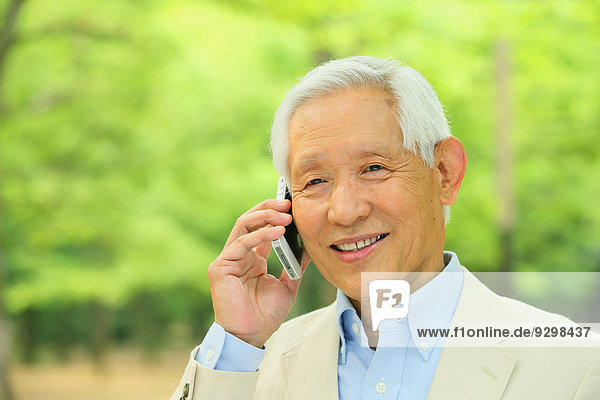 Senior adult Japanese man with smartphone in a park