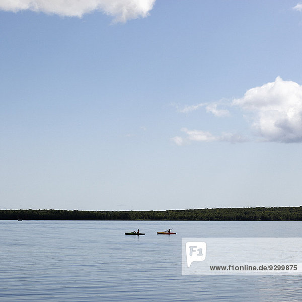 Zwei Personen in Kanus auf einem See