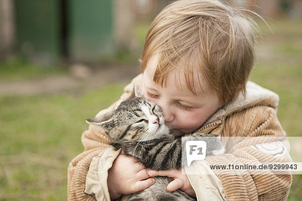 Kleines Mädchen mit Katze und Küssen