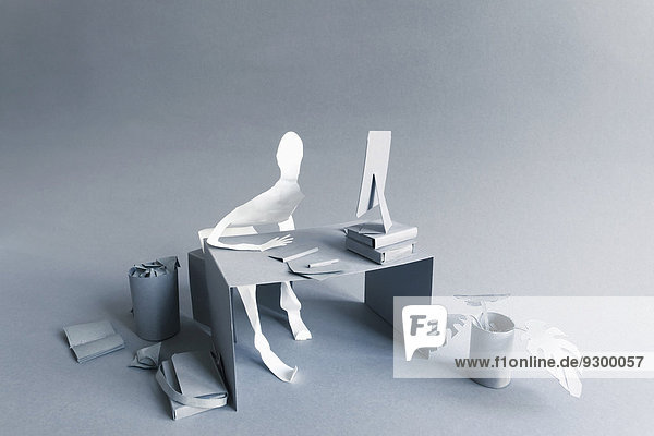 Gestresster Papierunternehmer am Schreibtisch über grauem Hintergrund
