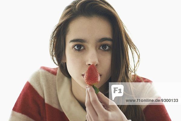 Mädchen hält Erdbeere vor dem Mund über weißem Hintergrund