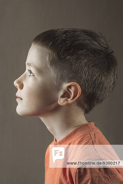 Profilaufnahme eines Jungen  der über den farbigen Hintergrund schaut.