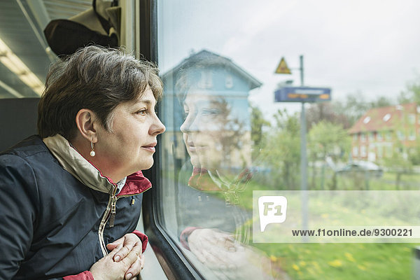 Reife Frau schaut durch das Zugfenster
