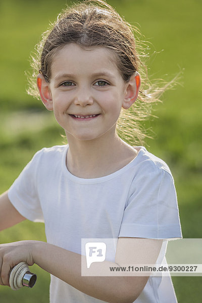 Portrait süßes lächelndes Mädchen mit Fahrrad im Park