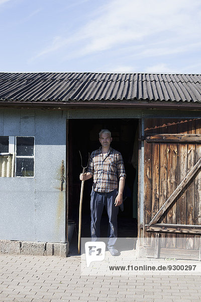 Porträt eines selbstbewussten reifen Mannes am Eingang der Geflügelfarm