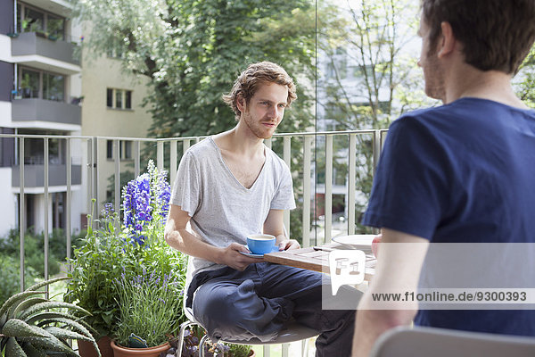 Gay man looking at partner while having coffee at porch
