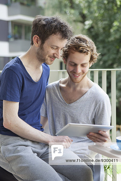 Gay couple using digital tablet at porch