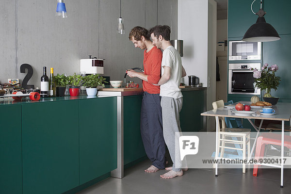Full length side view of young gay couple in kitchen