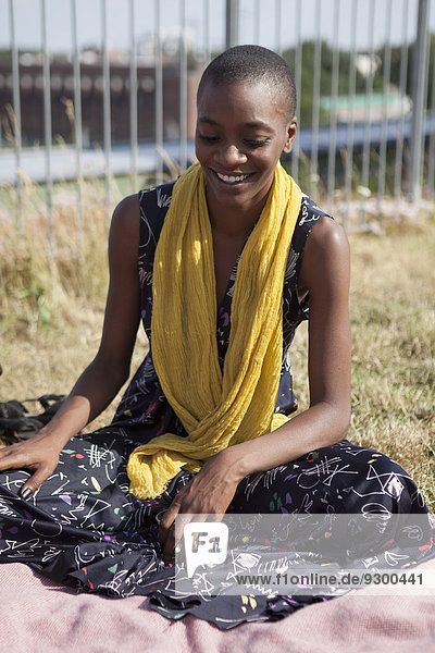 Fröhliche junge Frau sitzt auf der Terrasse Garten