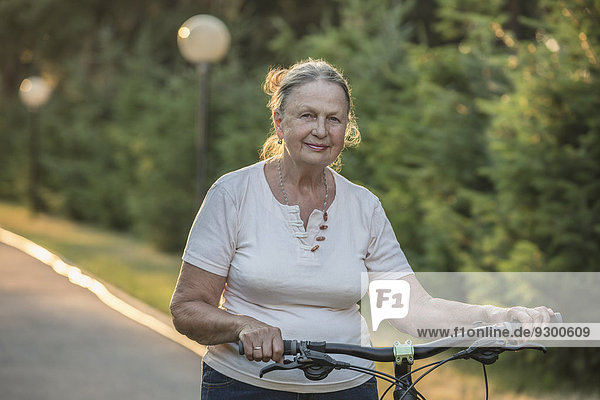 Portrait of senior woman with bicycle in park