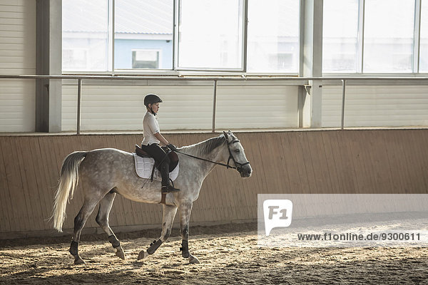 Seitenansicht des Jungen auf dem Pferd im Ausbildungsstall