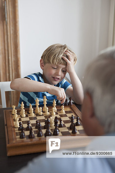 Kleiner Junge spielt Schach mit Großvater zu Hause