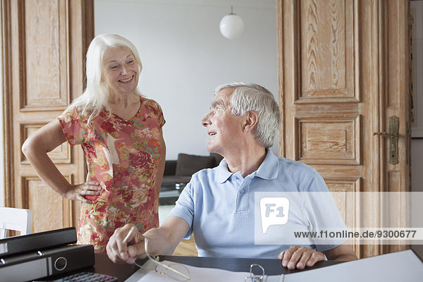 Älterer Mann  der die Frau bei der Berechnung der Hausfinanzierung am Tisch ansieht