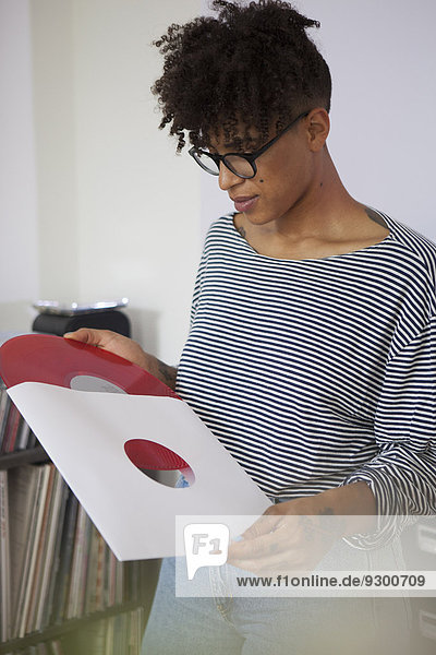 Junge Frau  die zu Hause Vinyl-Schallplatte von der Papierhülle nimmt