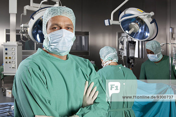 Porträt eines Chirurgen mit seinem Operationsteam im Hintergrund