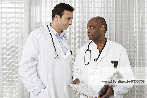 Two doctors in lab coats consulting over a medical file
