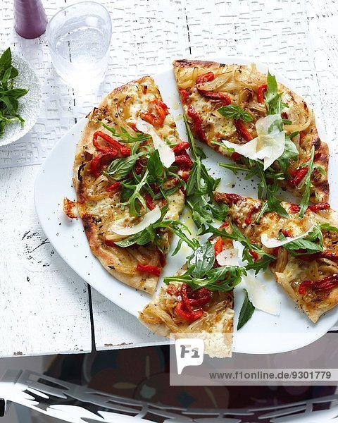Teller mit geschnittener Vollkornpizza mit Kräutern  Gemüse und Parmesan