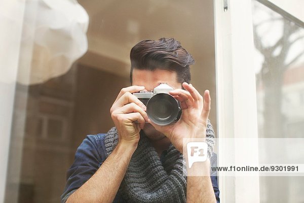 Porträt eines jungen Mannes  der mit einer Spiegelreflexkamera fotografiert.