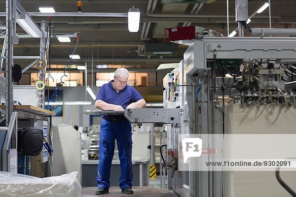 Arbeiter mit Maschine in der Papierverpackungsfabrik