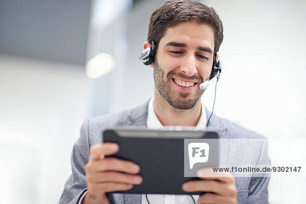 Young man wearing headset using digital tablet