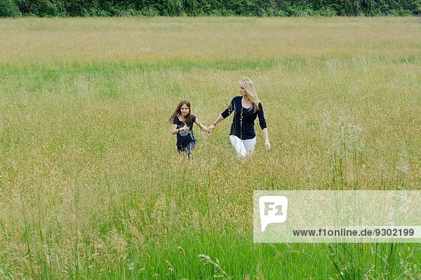 Mutter und Tochter beim Spaziergang durch das lange Grasfeld