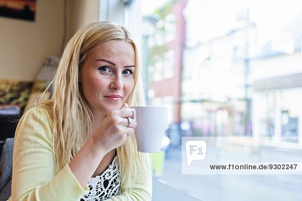 Portrait of mid adult woman drinking coffee in cafe