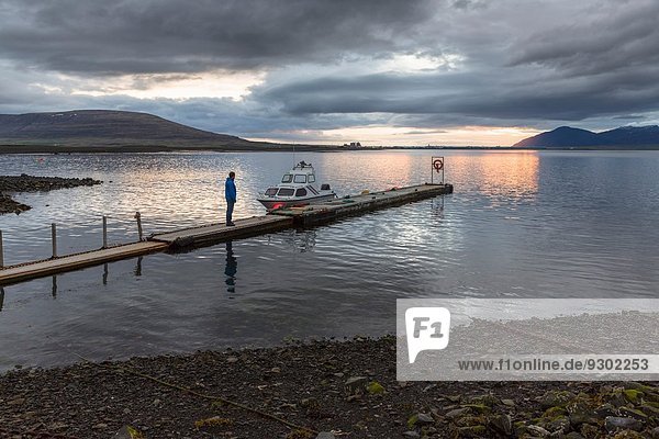 Man on pier at sunset Hvalfjordur Iceland